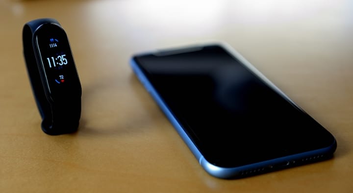 机に置かれたウェアラブル端末とスマートフォン