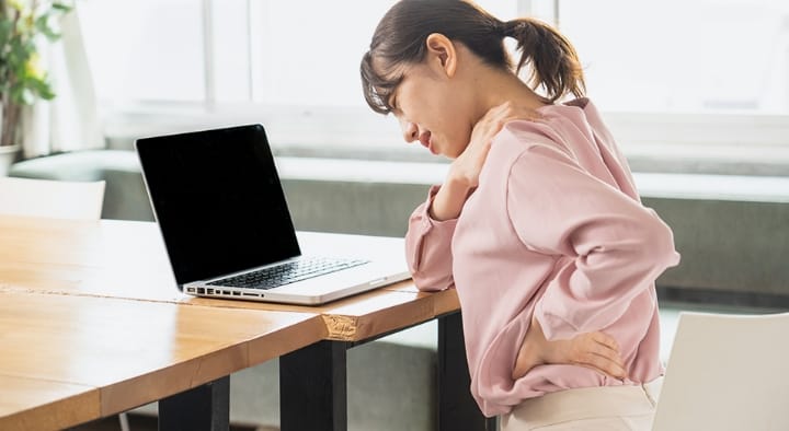 長時間のパソコン作業で肩と腰に不調を感じる女性