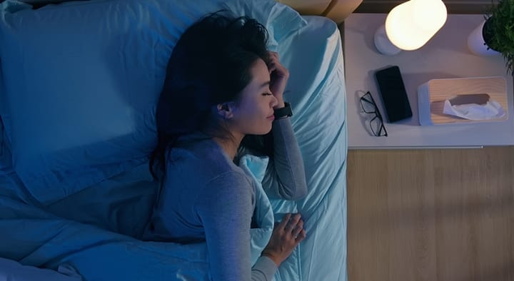 スマートウォッチをつけてベッドで眠っている女性